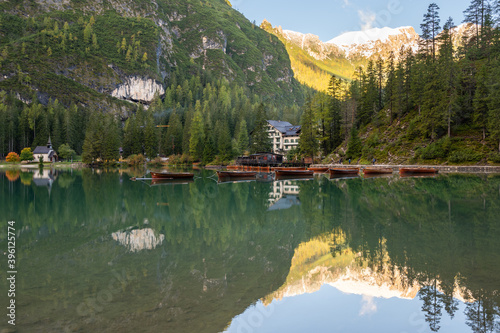 A view of the lake Pragser Wildsee in the Dolomites with a chain of boats, mountains and woods in autumn in South Tyrol, Italy.