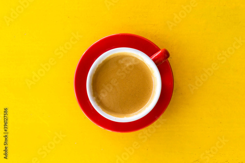 A photo of a red coffee mug on a yellow table