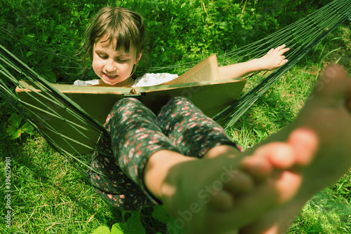 Learning always and everywher concept. Young beauutifuul girl reading book outdoors in hammock photo