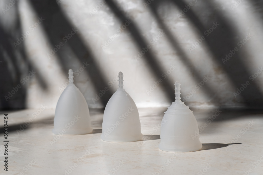 Different sizes of silicone menstrual cups on minimalist background with dark shadow. Reusable eco-friendly feminine hygiene products. Zero waste sustainable plastic free lifestyle Different sizes of silicone menstrual cups on minimalist background with dark shadow. Reusable eco-friendly feminine hygiene products. Zero waste sustainable plastic free lifestyle