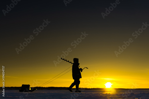 Winter fishing. Silhouette of a fisherman against the backdrop of a picturesque sunset. Copy space. Soft focus © Dmitry