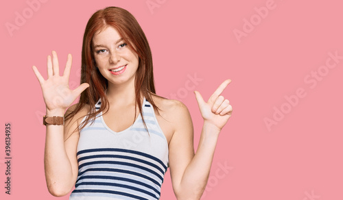 Young read head woman wearing casual clothes showing and pointing up with fingers number seven while smiling confident and happy.