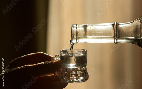 Palinka, the famous homemade Hungarian alcohol pouring from a bottle to glass. Stock photo from Hungary. 