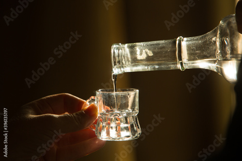 Palinka, the famous homemade Hungarian alcohol pouring from a bottle to glass. Stock photo from Hungary. 