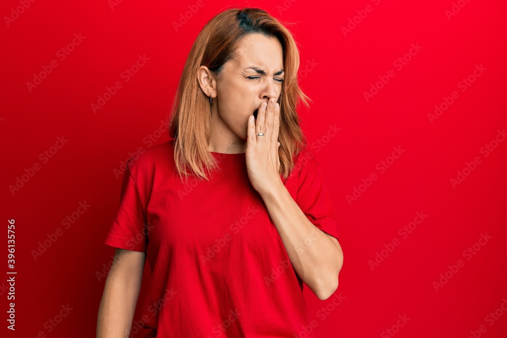 Hispanic young woman wearing casual red t shirt bored yawning tired covering mouth with hand. restless and sleepiness. Hispanic young woman wearing casual red t shirt bored yawning tired covering mouth with hand. restless and sleepiness.