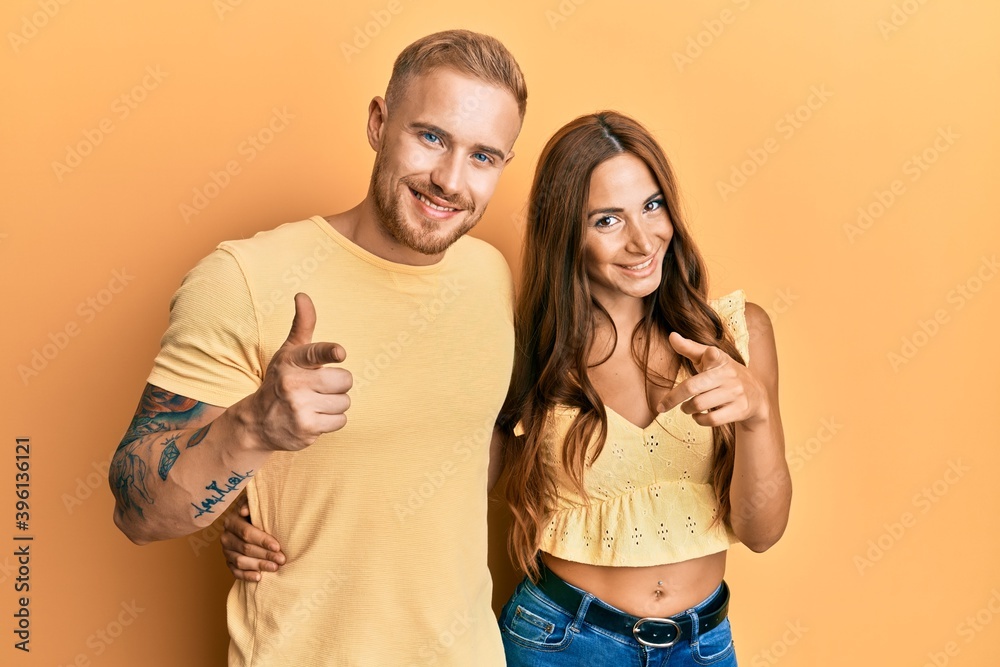 Fototapeta premium Young couple of girlfriend and boyfriend hugging and standing together pointing fingers to camera with happy and funny face. good energy and vibes.