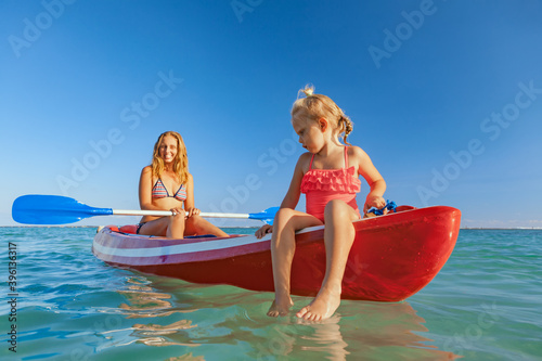 Happy family - young mother, children have fun on boat walk. Woman and child paddling on kayak. Travel lifestyle, parents with kids recreational activity, watersports on summer sea beach vacation. © Tropical studio