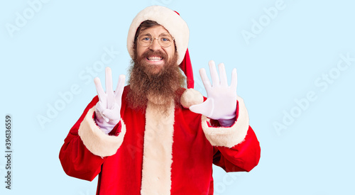 Handsome young red head man with long beard wearing santa claus costume showing and pointing up with fingers number eight while smiling confident and happy. photo