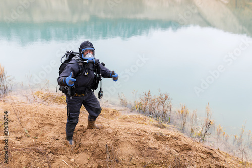 A lifeguard in a wetsuit is preparing to dive into the pond. Search at the bottom of the pond. © nazariykarkhut