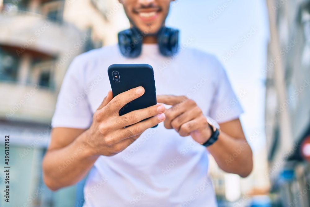 Young latin man smiling happy using smartphone and headphones at the city. Young latin man smiling happy using smartphone and headphones at the city.