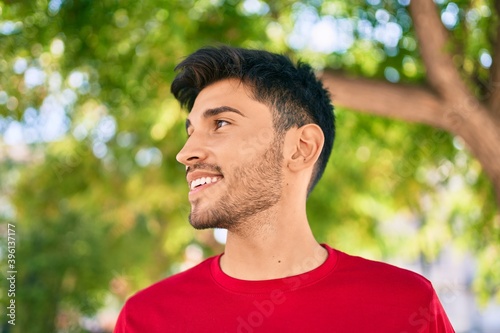 Young latin man smiling happy walking at the city.