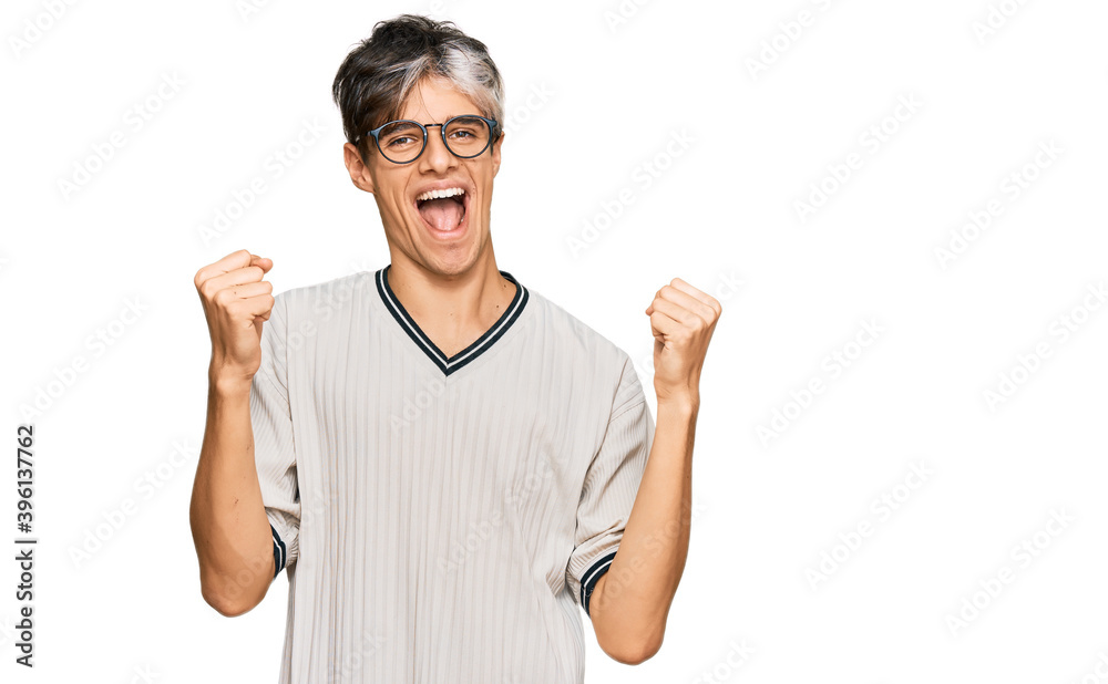 Young hispanic man wearing casual clothes and glasses screaming proud, celebrating victory and success very excited with raised arms Young hispanic man wearing casual clothes and glasses screaming proud, celebrating victory and success very excited with raised arms