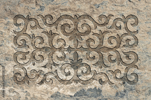 Ornamental print on the stone surface. Vintage ornament on the stone. Embossed drawing. Close-up. Stone texture. Pattern on the stone. Embossed pattern. Wallpaper. Tile
