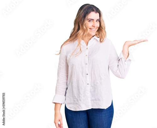 Young caucasian woman wearing casual clothes smiling cheerful presenting and pointing with palm of hand looking at the camera.