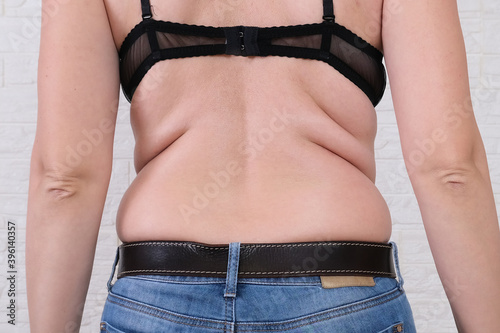 Young fat woman with excess weight, back view,flabby sides and back with folds of fat, overweighted fat body as s result of improper diet