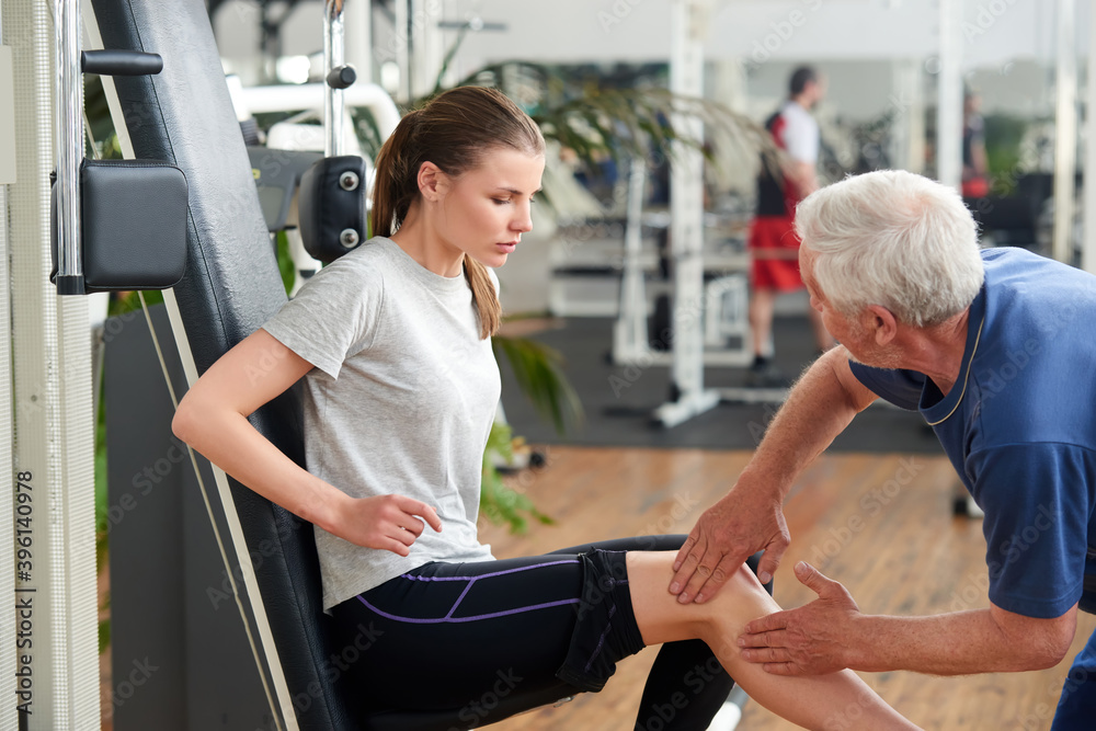 Young fit woman injured leg during workout. Male fitness instructor assisting young woman who had injured herself at the gym. Young fit woman injured leg during workout. Male fitness instructor assisting young woman who had injured herself at the gym.