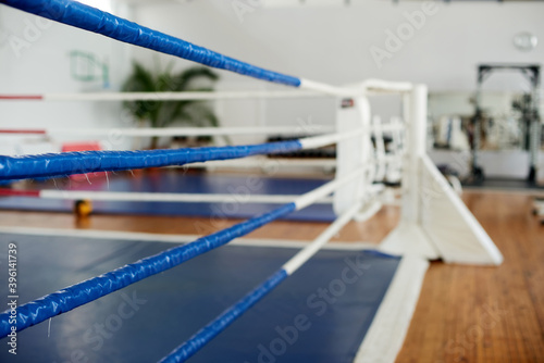 Empty boxing ring in the gym. Blue corner of a boxing ring surrounded by ropes in a gym interior.