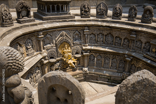 Ancient Hindu shrine in Kathmandu, Nepal. A dried fountain decorated with stone reliefs of gods with golden figures in the centre photo