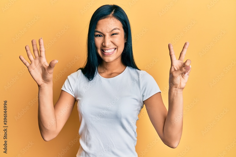 Beautiful hispanic woman wearing casual white tshirt showing and pointing up with fingers number seven while smiling confident and happy. Beautiful hispanic woman wearing casual white tshirt showing and pointing up with fingers number seven while smiling confident and happy.