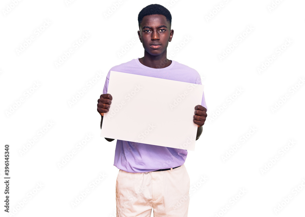Young african american man holding blank empty banner thinking attitude and sober expression looking self confident Young african american man holding blank empty banner thinking attitude and sober expression looking self confident