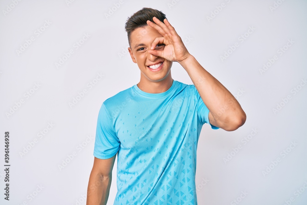 Young hispanic boy wearing casual clothes smiling happy doing ok sign with hand on eye looking through fingers Young hispanic boy wearing casual clothes smiling happy doing ok sign with hand on eye looking through fingers