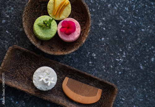 Variety of different natural eco friendly colorful solid shampoo bars, conditioner or soaps with wooden comb on stone background. Zero waste and sustainable plastic free lifestyle