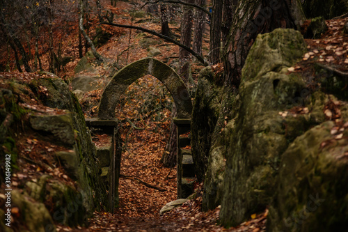 Stone arch fairytale portal with autumn leaves, Vranov castle gothic ruins with pantheon on steep sandstone rock cliff near village Mala Skala, Bohemian Paradise, Czech Republic