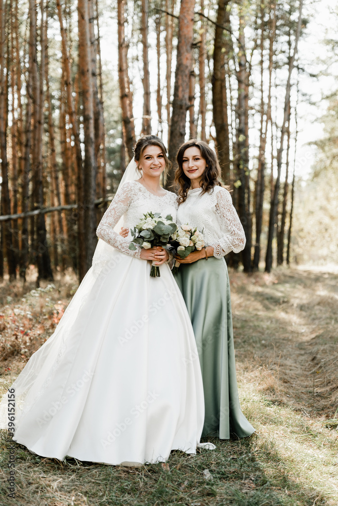 Tender bride with smiling bridesmaids dressed in long elegant dresses,bridesmaids with happy bride on wedding day. wedding bouquets are held by girlfriends, wedding day,