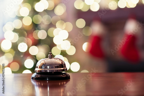 Silver vintage reception bell on desk of guesthouse, hotel and color shining garland on christmas tree on background. Christmas trave