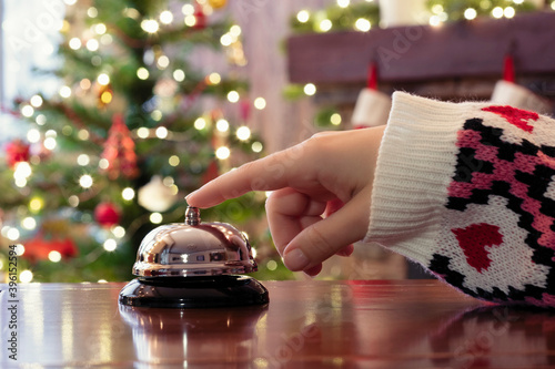 Valokuvatapetti Hand of guest ringing reception bell on desk of guesthouse, hotel at christmas time