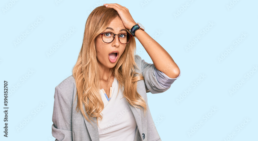 Beautiful blonde young woman wearing business clothes surprised with hand on head for mistake, remember error. forgot, bad memory concept. Beautiful blonde young woman wearing business clothes surprised with hand on head for mistake, remember error. forgot, bad memory concept.