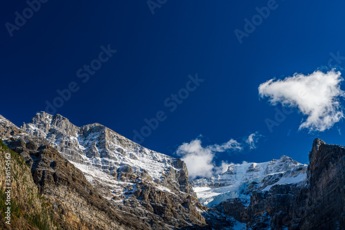 Snow-covered majestic mountain peaks with dark blue sky and flowing clouds in the background. Valley of the Ten Peaks, Moraine lake. Banff National Park, Canadian Rockies, Alberta, Canada.