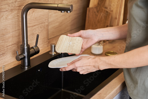 Woman wash dishes with organic eco friendly sponge. Zero waste concept photo