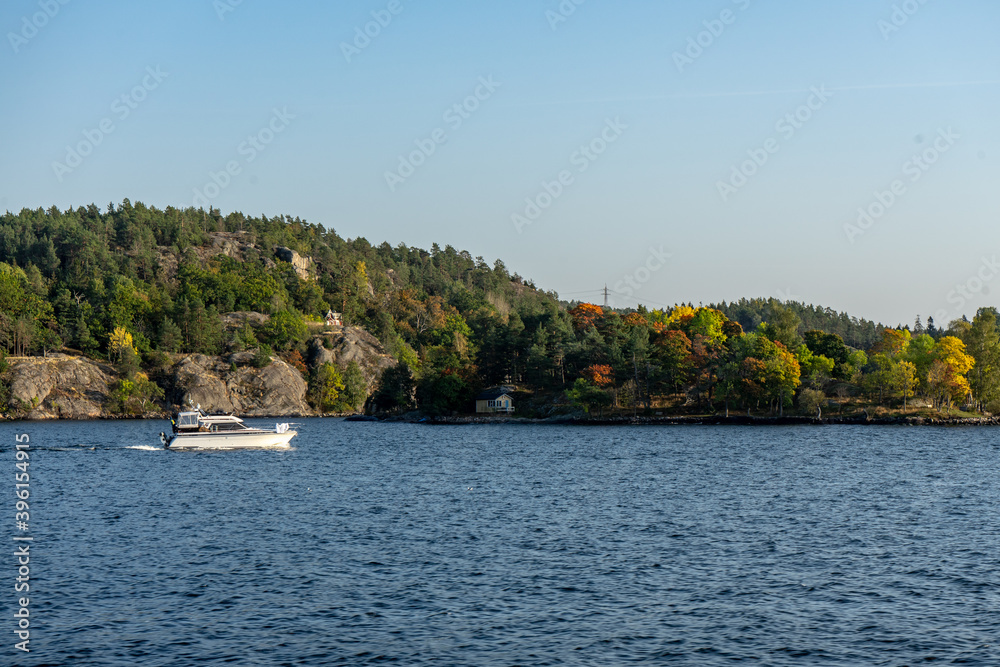 Small boat going by forest landscape in the Stockholm Archipelago