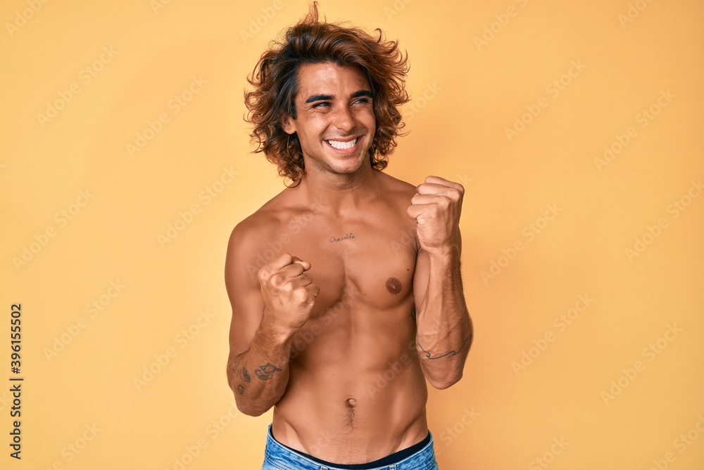 Young hispanic man standing shirtless celebrating surprised and amazed for success with arms raised and eyes closed. winner concept.