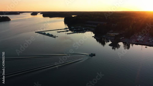 Aerial view following a motorboat arriving at a harbor, sunny morning, in the Saaristomeri archipelago of Turku, Finland - pan, dDrone shot photo