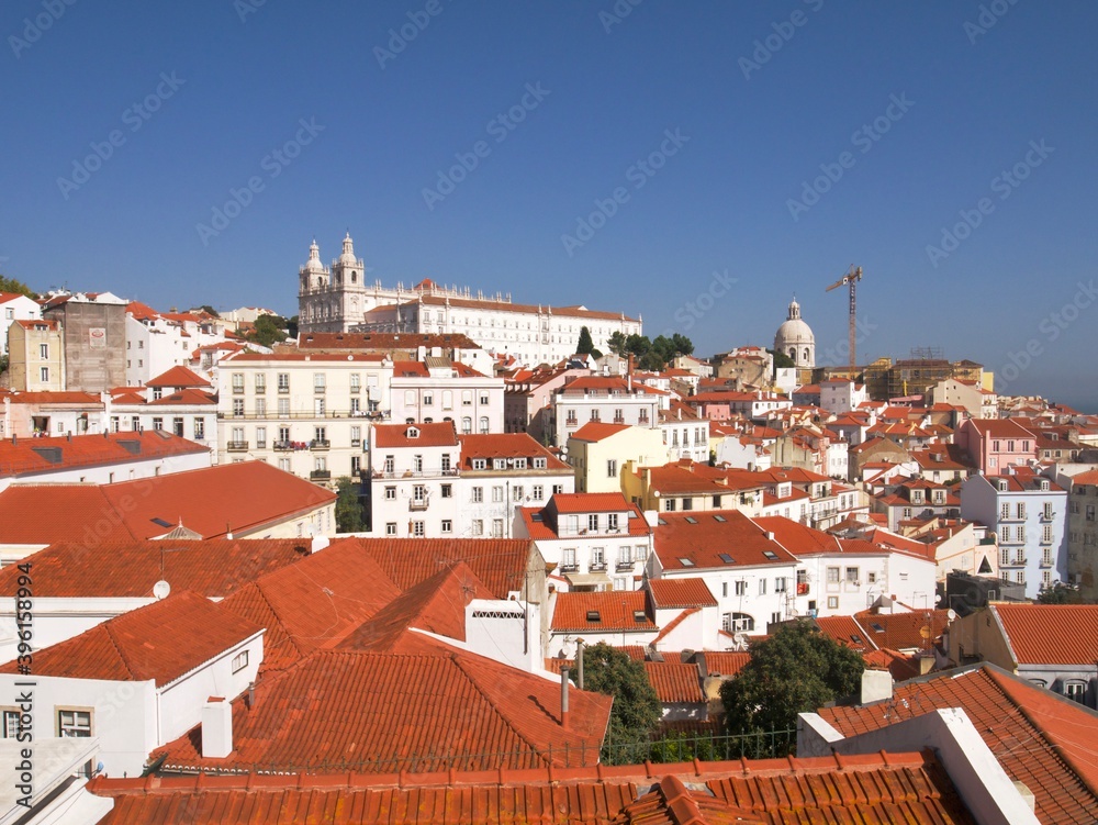Famous view of Lisbon's white cathedral and white houses with red roof under a blue sky