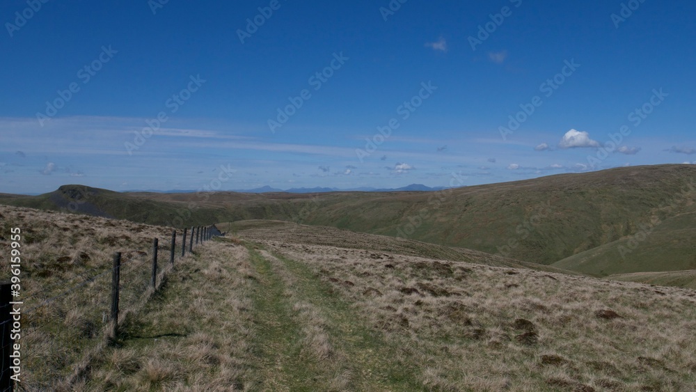 fence between pastures on top of Scottish hills on a hot summer day