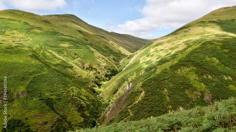 Naklejka premium beautiful lush green valley between two hills in Scotland