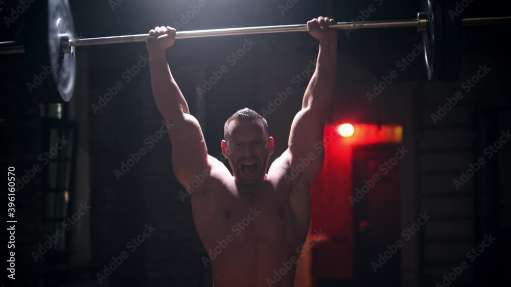 Tough man in the gym doing exercises - pulling up a heavy bar with an effort Tough man in the gym doing exercises - pulling up a heavy bar with an effort