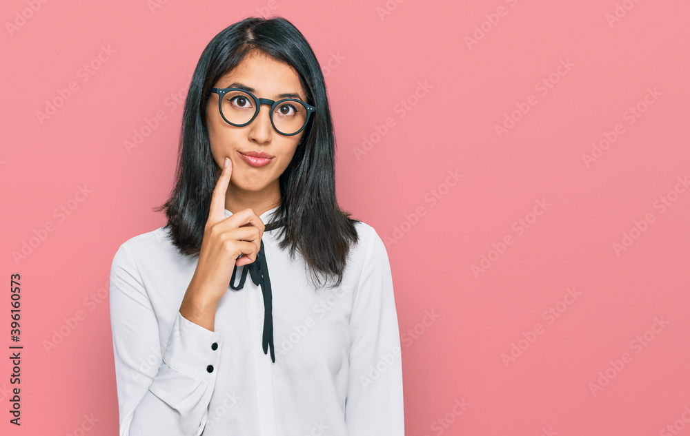 Beautiful asian young woman wearing business shirt and glasses serious face thinking about question with hand on chin, thoughtful about confusing idea