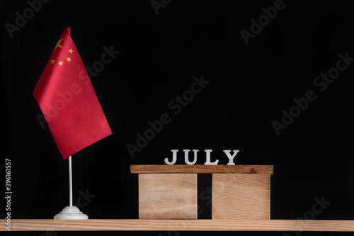 Wooden calendar of July with Chinese flag on black background. Holidays of China in July.