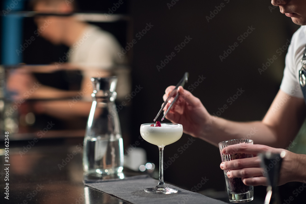 Close-up of the process of preparing a cocktail with liqueur at a party of friends in a nightclub. The dark blurred background