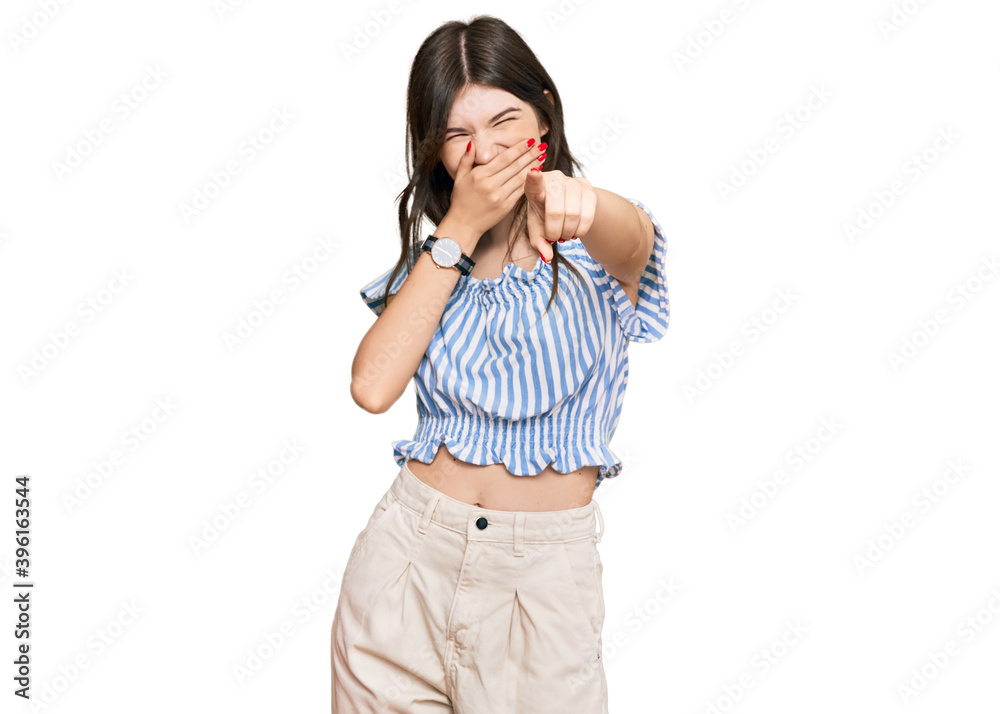 Young beautiful caucasian girl wearing casual clothes laughing at you, pointing finger to the camera with hand over mouth, shame expression Young beautiful caucasian girl wearing casual clothes laughing at you, pointing finger to the camera with hand over mouth, shame expression