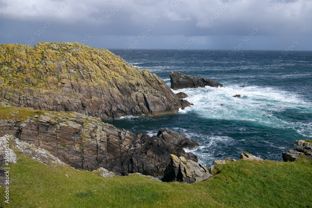 Wild blue ocean waves crushing against the cliffs on the northernmost point of the Outer Hebrides