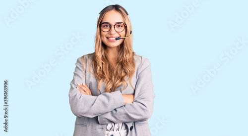 Young beautiful blonde woman wearing call center agent headset happy face smiling with crossed arms looking at the camera. positive person.