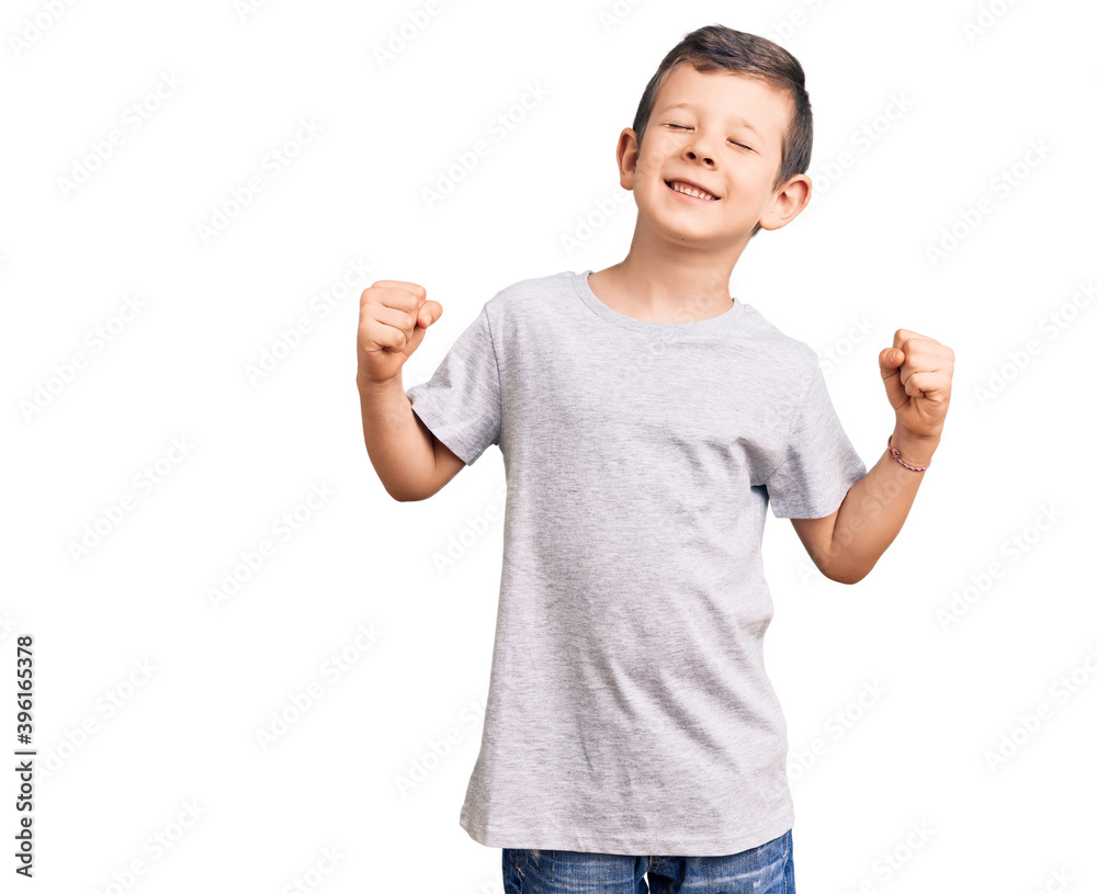 Cute blond kid wearing casual clothes very happy and excited doing winner gesture with arms raised, smiling and screaming for success. celebration concept. Cute blond kid wearing casual clothes very happy and excited doing winner gesture with arms raised, smiling and screaming for success. celebration concept.