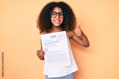 African american child with curly hair wearing glasses showing a passed exam smiling happy and positive, thumb up doing excellent and approval sign