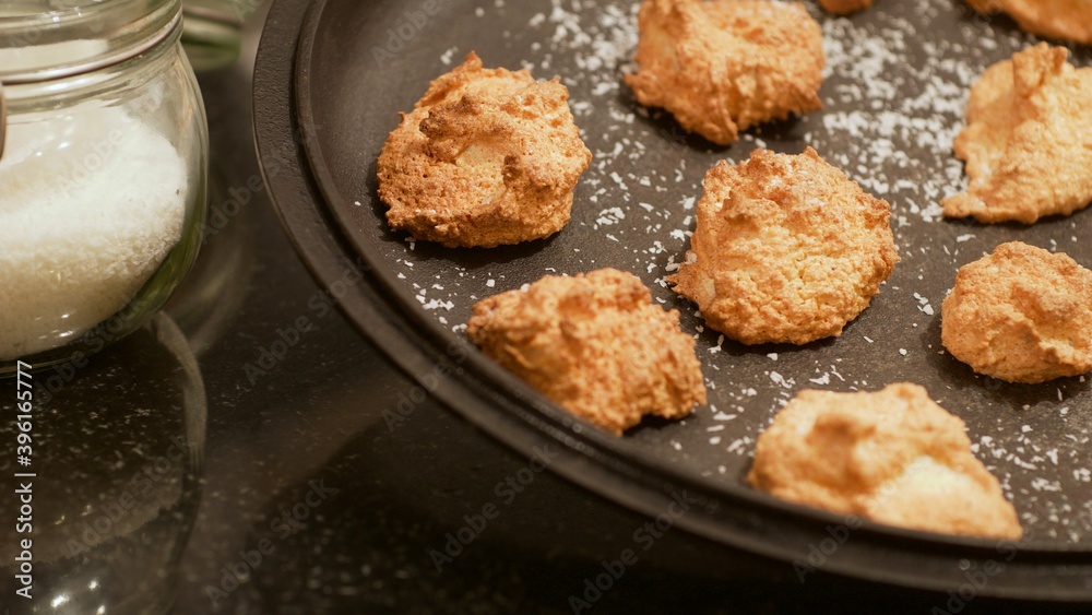 Soft golden coconut cookies shaped like clouds on a black plate sprinkled with coconut Soft golden coconut cookies shaped like clouds on a black plate sprinkled with coconut