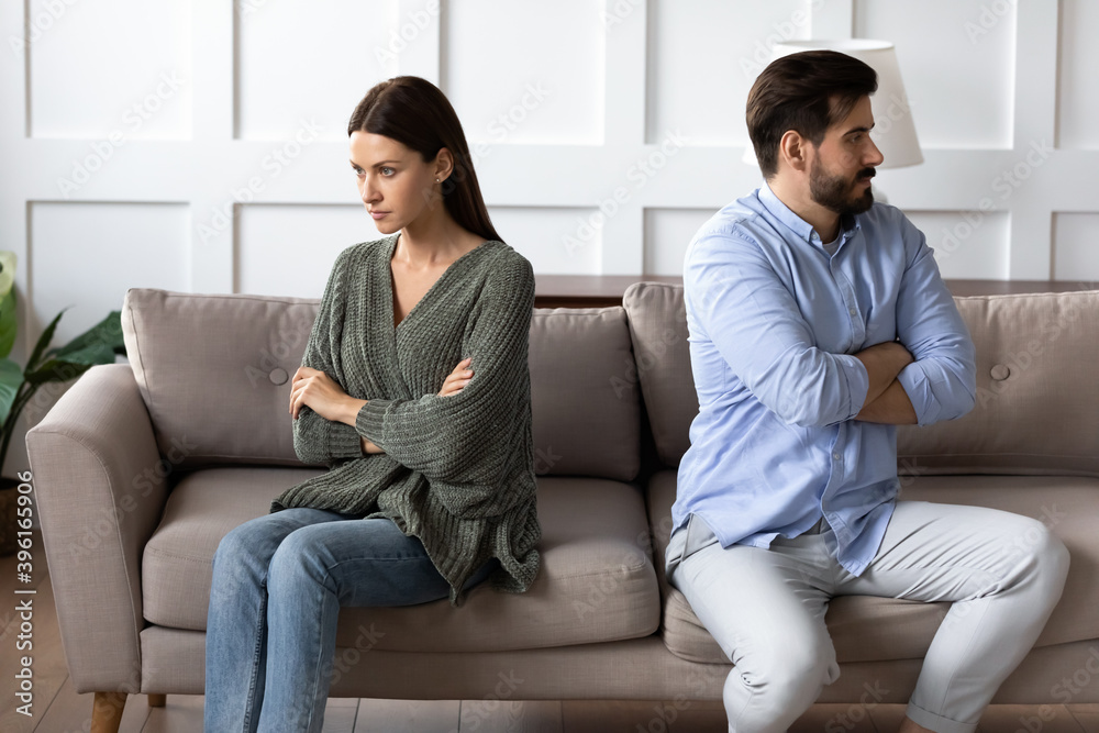 Stubborn angry man and woman spouses sit separate on sofa at home ignore each other avoid talking after fight. Unhappy mad young Caucasian couple think of divorce breakup after family fight quarrel. Stubborn angry man and woman spouses sit separate on sofa at home ignore each other avoid talking after fight. Unhappy mad young Caucasian couple think of divorce breakup after family fight quarrel.